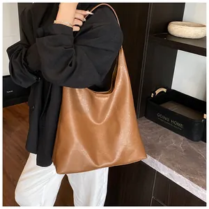 Detailed texture of a brown soft leather hobo bag worn by a model in a minimalist setting