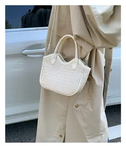 Detail showing cream woven texture and detachable strap on the bucket handbag