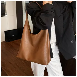 Detailed close-up of large caramel brown leather tote bag worn on shoulder by model