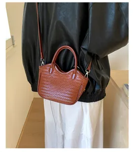 Detailed view of brown woven leather bucket bag with silver hardware and shoulder strap