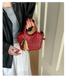 Detailed close-up of red woven bucket bag with handcrafted bead pendant and round handles