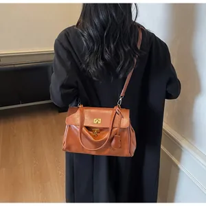 Detailed back view of a caramel brown leather tote bag worn with a black long coat