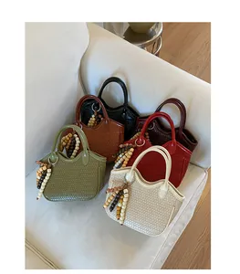 Close-up of woven bucket bags in green, tan, black, burgundy, and beige on a sofa