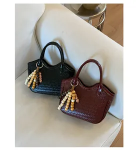Close-up of woven bucket bags in black and burgundy with decorative beaded tassels