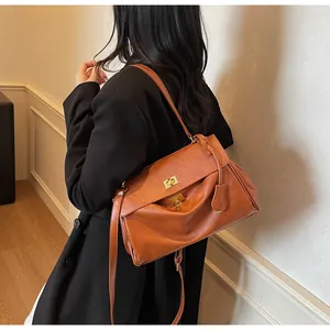 Detail of vintage brown leather tote bag with gold buckle and pleated side construction