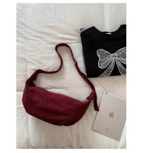 Détail du sac hobo en daim bordeaux avec texture mate et bandoulière à nœud élégante