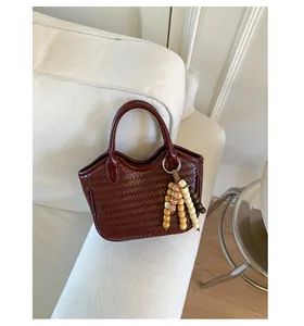 Macro detail of dark red woven texture and colorful wooden bead ornament on the bucket bag
