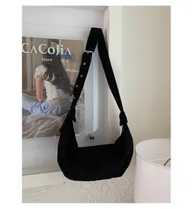Détail du sac hobo en daim noir avec large bandoulière réglable et boucle en métal