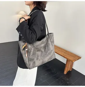 Detailed side view of large vintage tote bag with wood bead tassels on a model