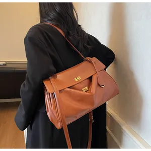 Brown leather tote bag featuring dual golden metal twist locks and adjustable shoulder strap