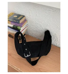 Détail du sac hobo en daim noir avec bandoulière réglable et boucle argentée sur bois