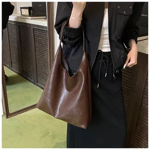Detail of a deep brown pleated leather tote bag showing high-capacity design and soft texture
