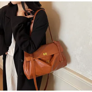 Detail of caramel leather tote bag showing gold dual twist-lock hardware on a model