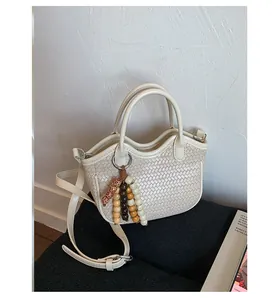 Detail of cream woven bucket bag showing intricate texture and decorative wooden beads