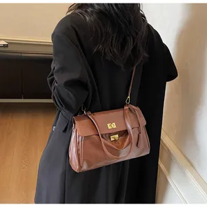 Detail view of a brown vintage tote bag with gold twist locks worn on a black wool coat