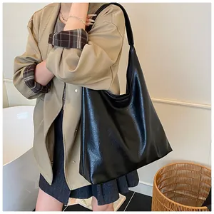 Detail of minimalist black hobo bag in glossy leather finish for daily commuters