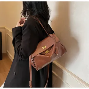 Brown leather tote bag featuring golden twist-lock closures and adjustable strap detail