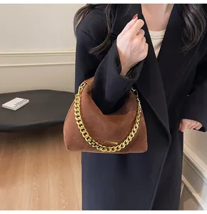 Close-up of a brown suede tote bag featuring a chunky gold chain and leather handle