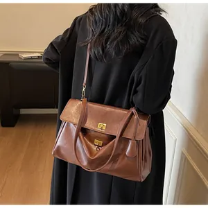 Detail of a dark brown vintage tote bag with gold lock and adjustable strap in use