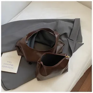 Detail view of deep brown large tote bag with matching zippered pouch on grey blazer background