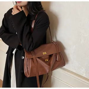 Detailed view of brown leather tote bag with golden twist locks worn by a model