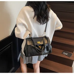 Detail of black tote bag with gold twist lock and adjustable shoulder strap on stairs