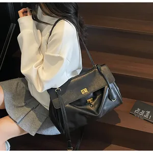 Side view of black leather tote bag with gold metal twist locks on a dark staircase