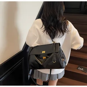 Close-up of black leather tote with dual gold twist locks and adjustable shoulder strap