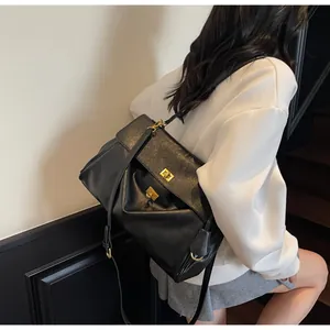 Detail of a black leather tote bag featuring a golden metal twist lock and slim shoulder strap