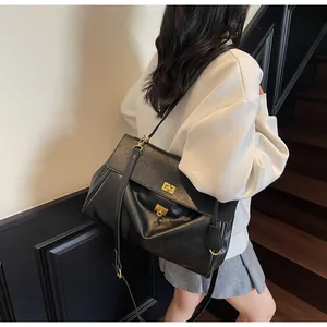 Detail of black lychee leather tote bag featuring gold turn-lock and adjustable strap