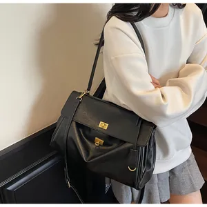 Detail of black faux leather tote with textured finish and gold metal buckle closure