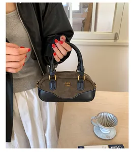 Detalle del bolso Boston de ante marrón oscuro con asas negras y logotipo dorado chic
