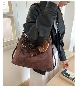 Detailed texture of dark brown suede tote bag with leather strap and donut charm