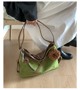 Detail of green suede hobo bag with brown leather straps and plush donut pendant