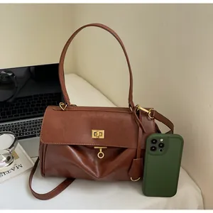 Close-up of textured brown tote bag featuring gold twist lock and smooth faux leather