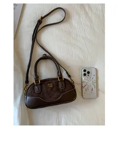 Detalle del bolso Boston de ante y cuero con costuras blancas y herrajes dorados