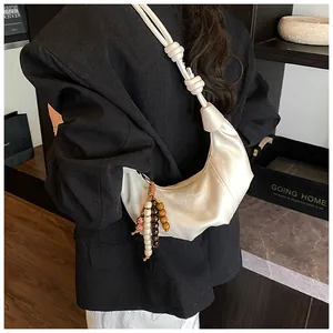 Detail of cream white crescent bag with colorful bead tassel and knotted strap details