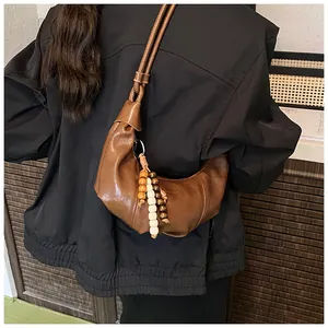 Detail of a brown crescent shoulder bag with wooden beads and a thin cord strap