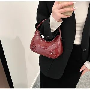 Primer plano del bolso media luna rojo oscuro con hebillas plateadas en modelo