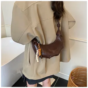 Deep brown crescent hobo bag made of glossy faux leather with decorative beaded tassel