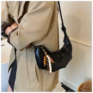 Detail of black crescent shoulder bag with wooden bead charm and knotted strap detail