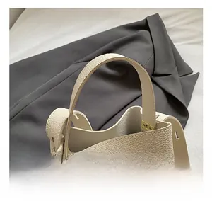 Detail of cream lychee texture leather handbag featuring a wide comfortable top handle