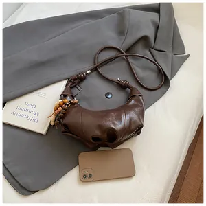 Detail of brown pleated crescent bag with wooden bead tassel and size reference