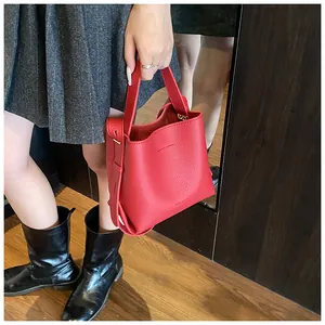Macro detail of red lychee textured leather bucket bag with seamless handle and logo