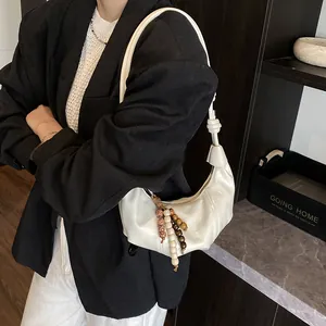 White crescent dumpling bag with wooden bead fringe and glossy faux leather finish