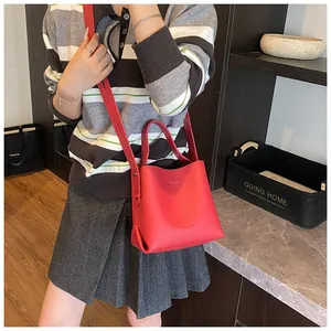 Side view of a red lychee pattern bucket bag with a long strap in a modern setting