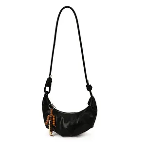 Minimalist black crescent shoulder bag with wooden bead charm and side knot detail