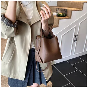 Close-up of deep brown lychee texture leather bucket bag with top handle and strap