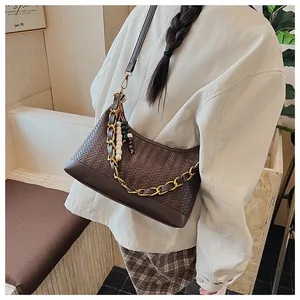 Détail du sac hobo tissé marron foncé avec chaîne dorée et breloque en perles