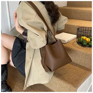 Close-up of deep brown lychee grain leather bucket bag with wide shoulder strap